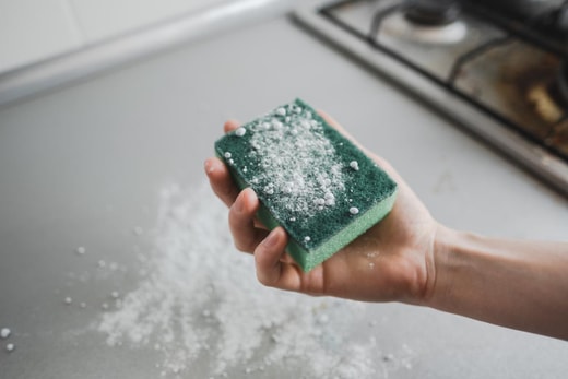 Green sponge with a cleaning powder in hand, kitchen cleaning.