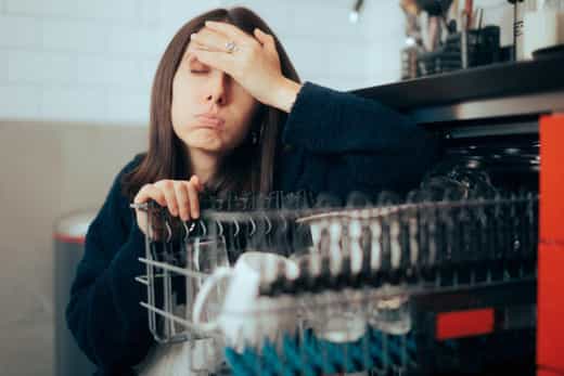 Stressed Unhappy Woman Dealing with Dishwasher Malfunction. Unhappy lady having problems with her new appliance doing tedious chore