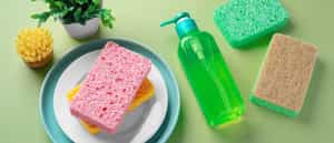 Natural cleaning sponges and brush with with dish washing liquid on green background